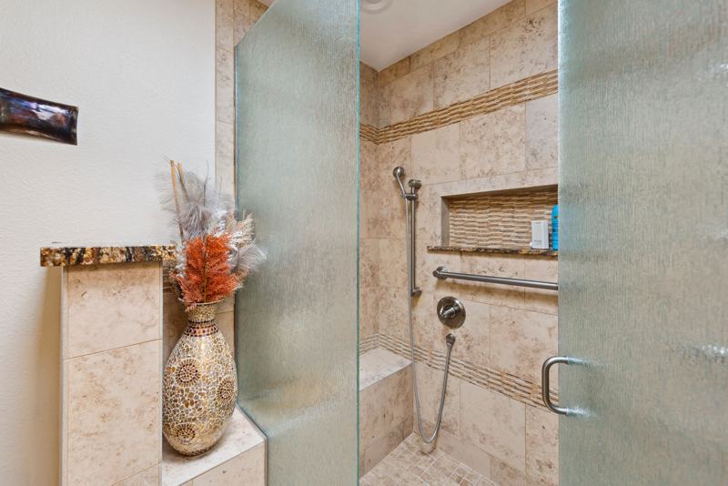 Primary bathroom walk-in shower with bench seating and dual showerheads